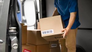 homem de camisa azul segurando caixa para enviar encomenda