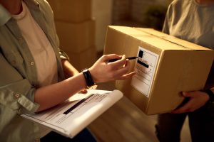 Moça jovem conferindo o endereço no pacote para envio de encomendas.
