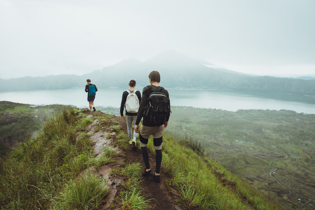 Como fazer trilha: imagem mostra 3 homens caminhando ao longo de uma colina.