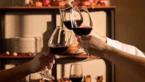 Jovens reunidos brindando uma taça de vinho enquanto realizam enoturismo no Vale do Paraíba.