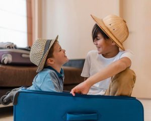 São Paulo com crianças: dois meninos pequenos com chapéus brincando dentro de uma mala azul.