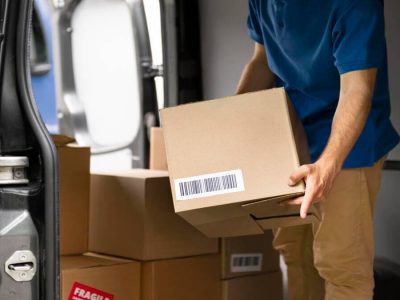 homem de camisa azul segurando caixa para enviar encomenda